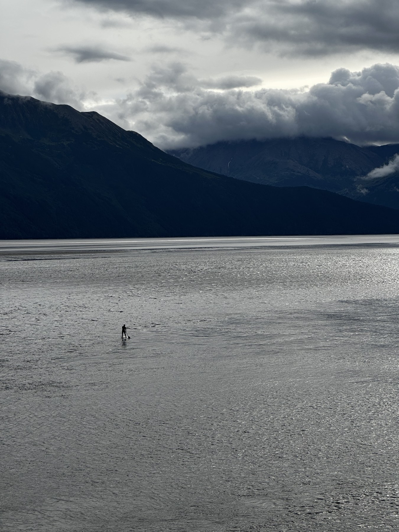Lone paddleboarder on Turnagain Arm before the bore tide arrives, Chugach peaks behind