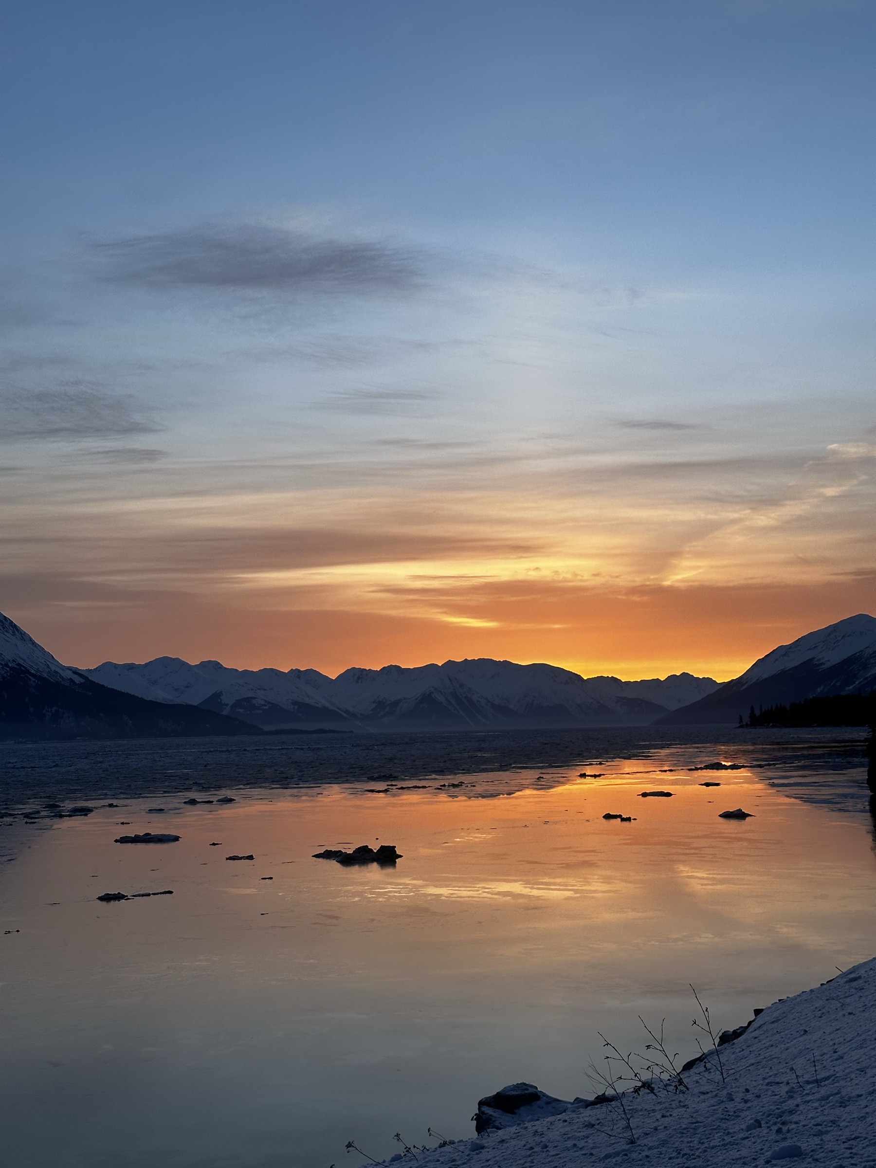 Winter sunrise over a frozen Turnagain Arm from Hope, orange and gold sky reflected in ice, Chugach Mountains silhouetted