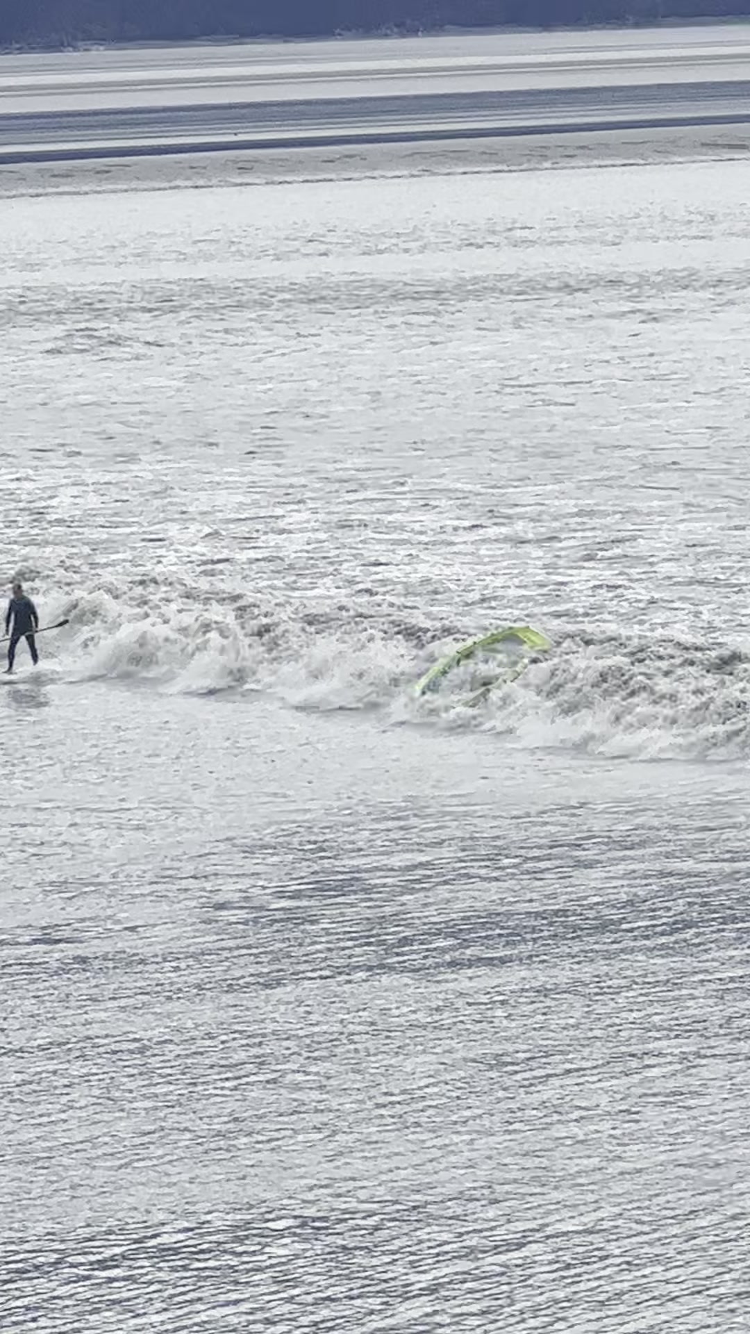 Wingsurfer riding the bore tide wave with green wing at Girdwood